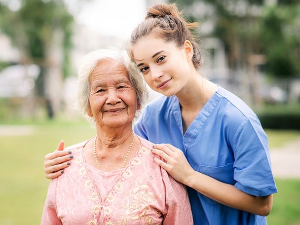 elderly woman with female nurse in scrubs
