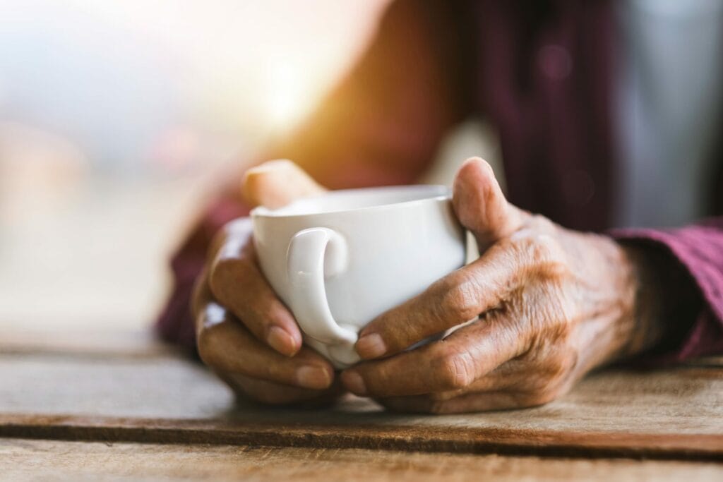 elderly man holding coffee cup