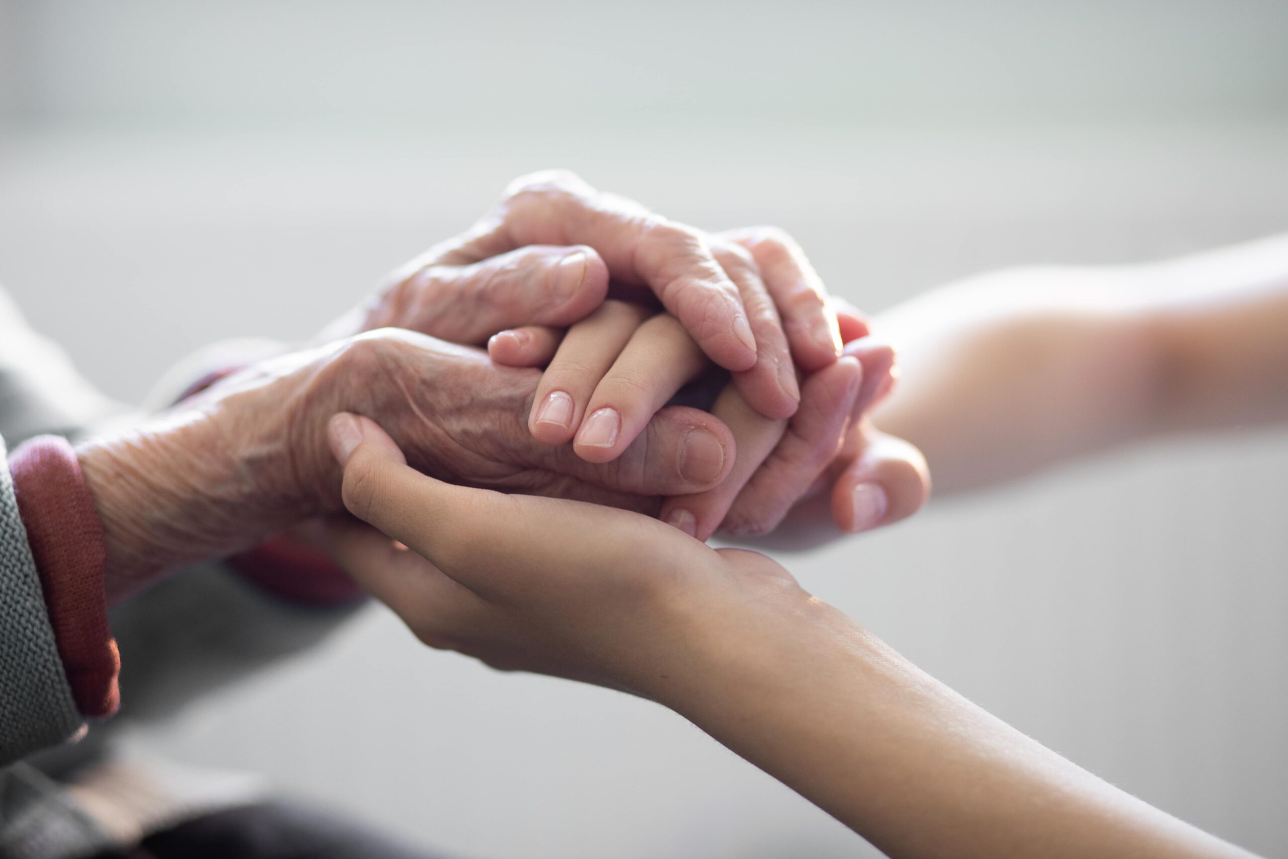 Elderly hands holding youth hands during end-of-life